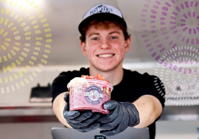 A Buoy Bowls employee smiling and holding an açaí bowl
