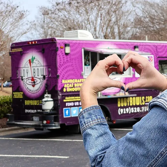 Girl giving heart-hands to the Buoy Bowls purple truck