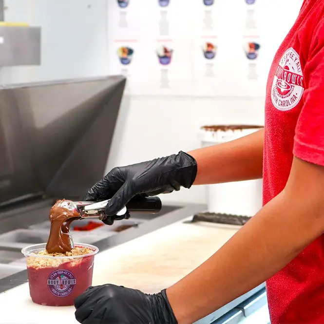 A Buoy Bowls employee putting Nutella on an açaí bowl