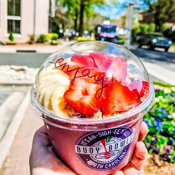 Holding a Buoy Bowls açaí bowl with enjoy written on it