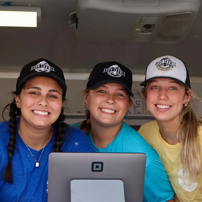 Three Buoy Bowls employees smiling in the window of the purple truck
