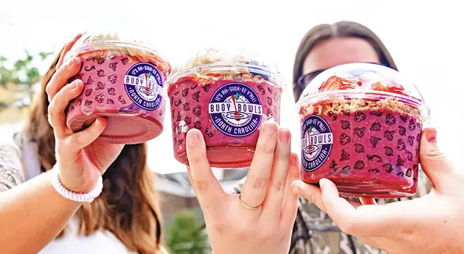 Catering customers holding up 3 Buoy Bowls açaí bowls