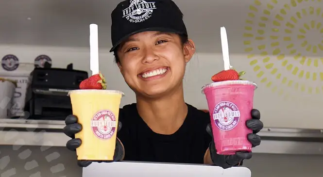 Buoy Bowls employee in food truck window holding two smoothies